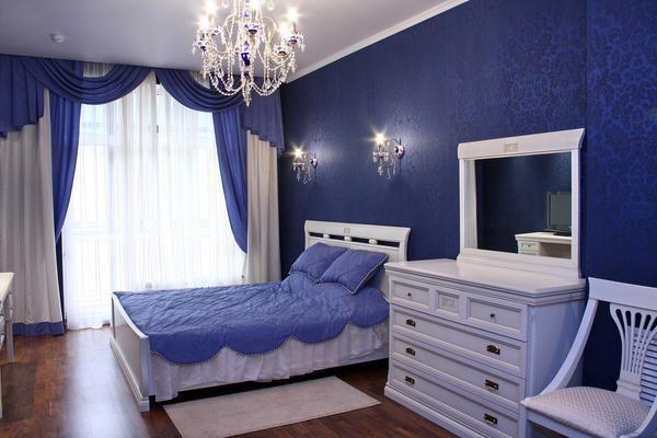 Белая классическая мебель выделяется на фоне синих стен, благодаря чему комната не кажется монотонной и скучной 
