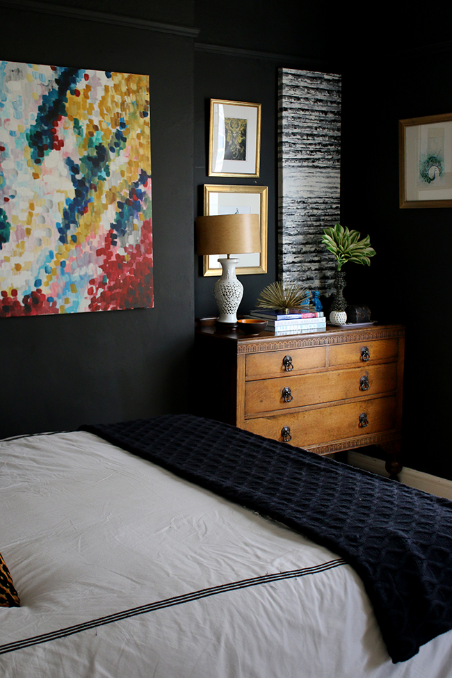 black bedroom with vintage dresser and bright colourful art - see more on www.swoonworthy.co.uk